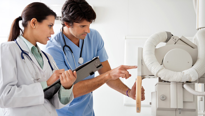 female doctor and male nurse reading results on medical equiptment