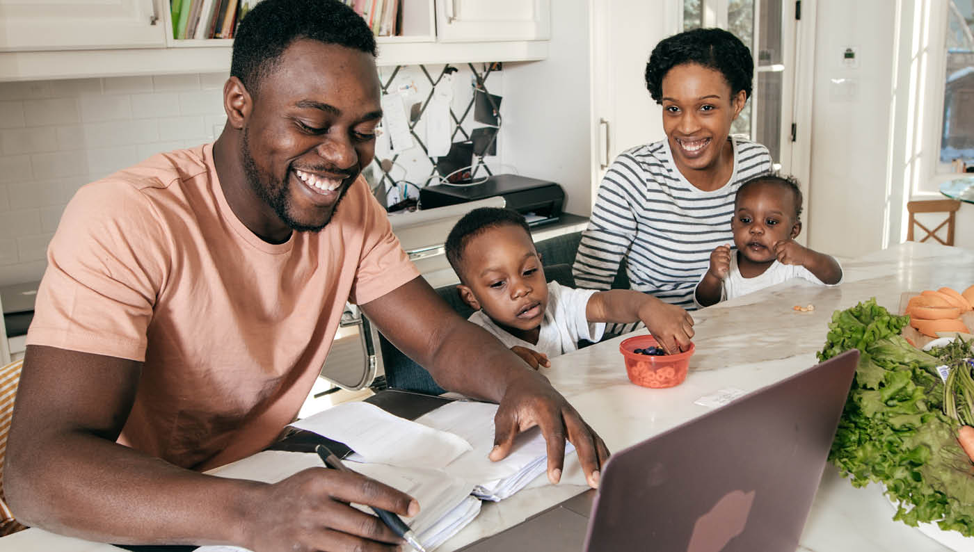African American Man on Laptop surrounded by wife and kids