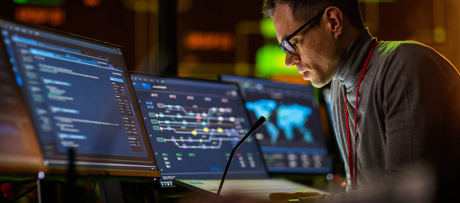 cybersecurity expert works in front of multiple computer screens