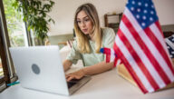 Woman veteran working at a computer with “Can I get full BAH for online classes?” written underneath