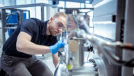 Gloved man in goggles and polo shirt working on nuclear technology