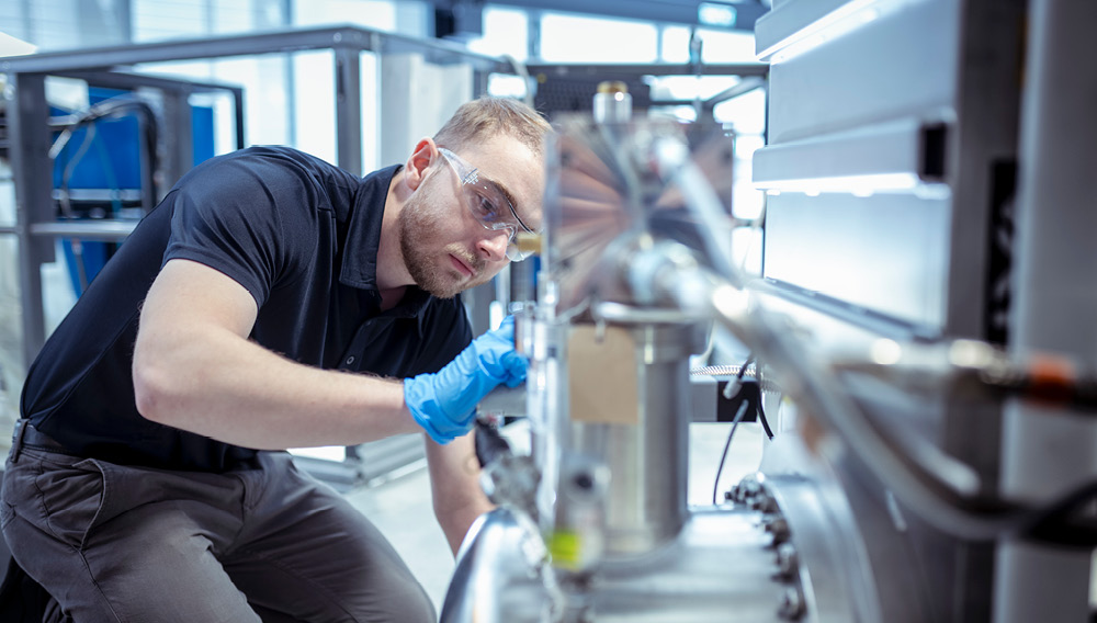 Gloved man in goggles and polo shirt working on nuclear technology