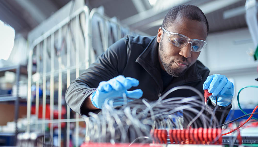 Technician in goggles and latex gloves performing system maintenance on electronic device