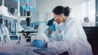Scientist peering through a microscope in a lab, hoping to make the next medical breakthrough