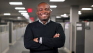 Khamel Abdulai with his arms folded, standing in the hallway.