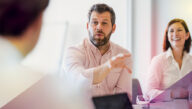Consultant in rolled-up sleeves making a point in a boardroom