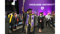 Graduate Jatik Gibbs-Judd raises the Excelsior Alumni Torch at the 2025 Commencement ceremony.