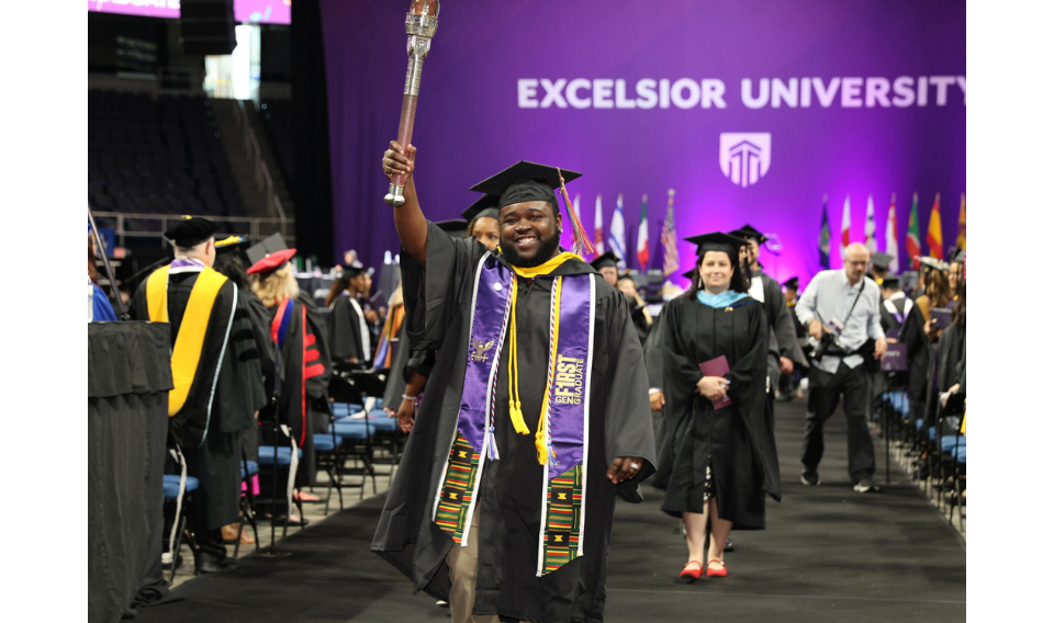 Graduate Jatik Gibbs-Judd raises the Excelsior Alumni Torch at the 2025 Commencement ceremony.