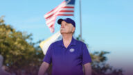 Richard Cole in Excelsior University purple walks under the American flag.