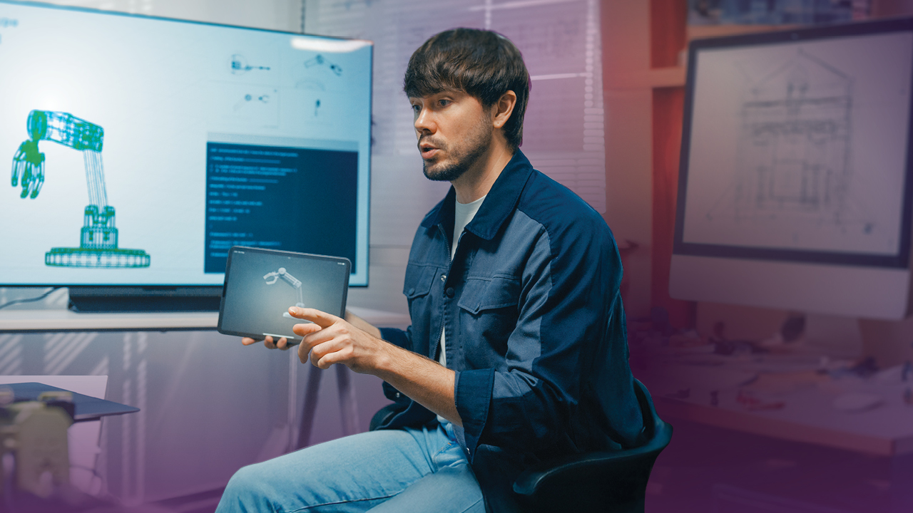A young mechanical engineering technologist sits in a work studio and holds up a computer-aided design of a robotic arm.